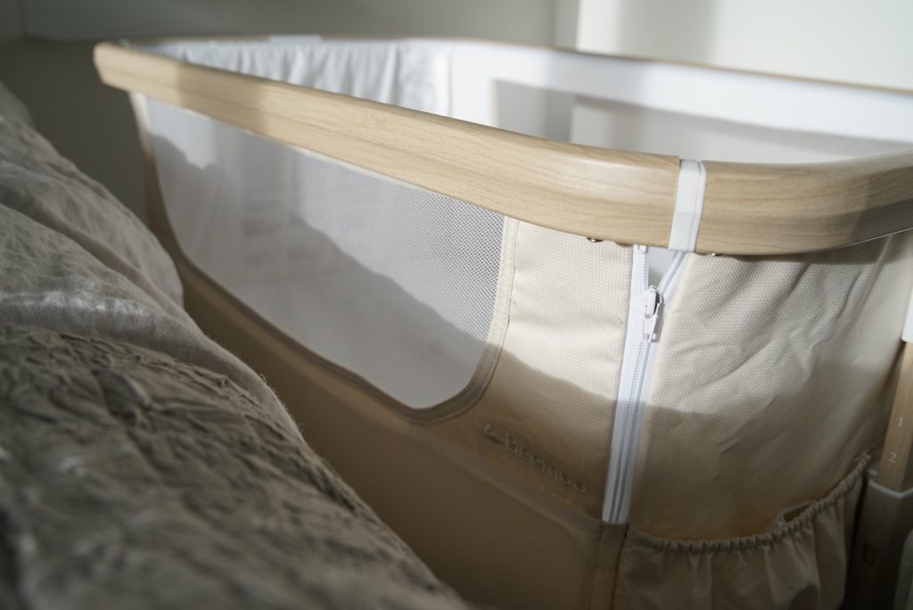 närbild på ram, meshparti och nedfällningsbar sida på beemoos bedside crib